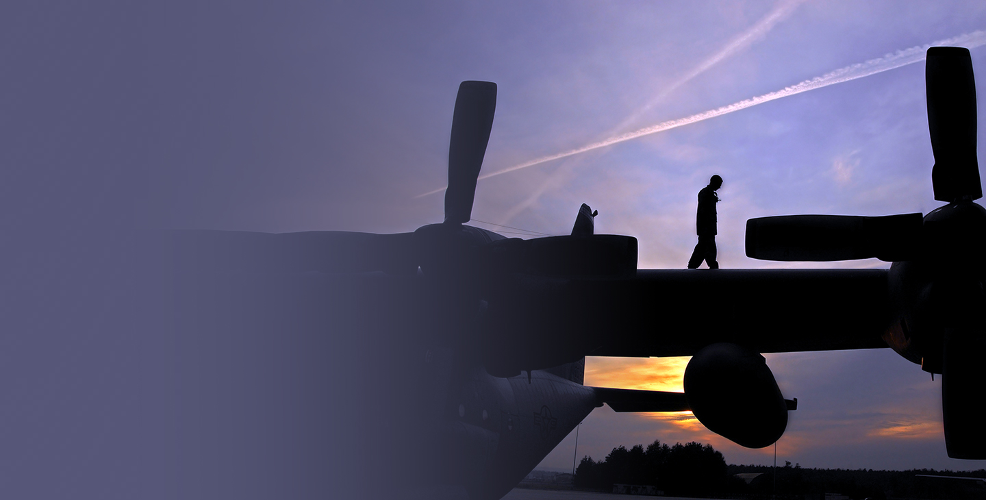 Soldier on the wing of a military aircarft at sunset