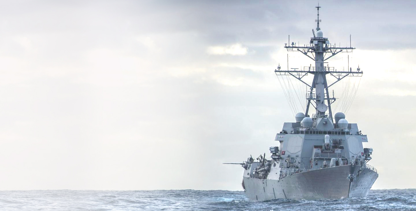 Large gray warship at sea with various UHF SATCOM antennas