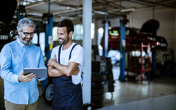 2 business internet customers looking at iPad inside a car repair shop