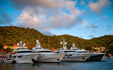 Four charter yachts sitting in a bay next to a luscious mountain