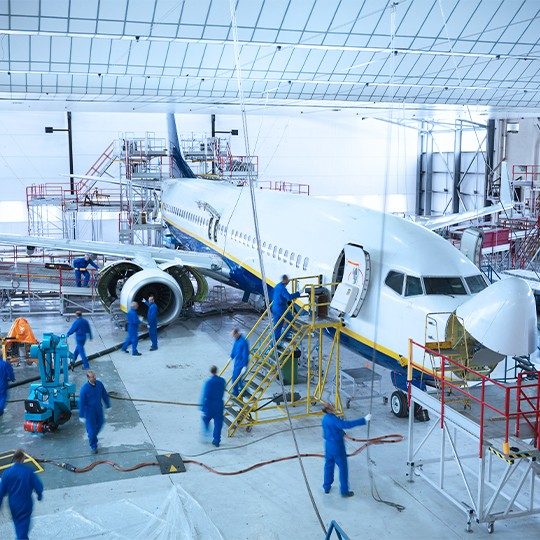Team of airplane technicians working on a commercial plane inside a hanger