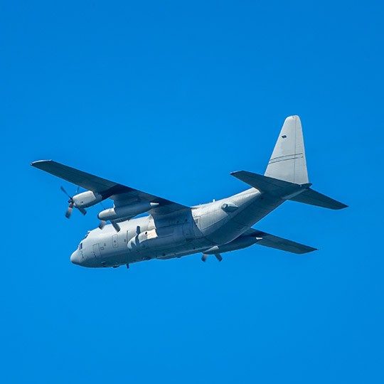 Mulitary aircraft flying against a bright blue sky